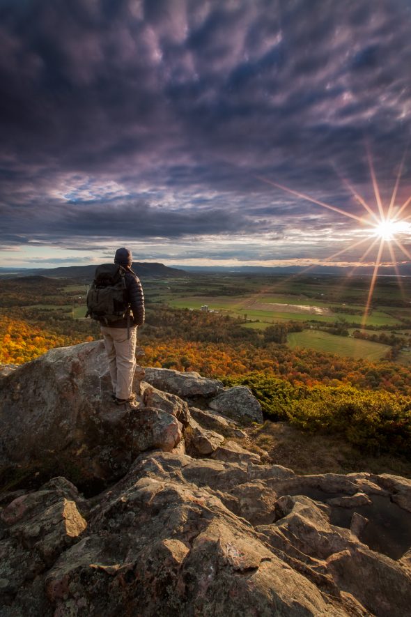 photographer standing on top of mountain at sunset