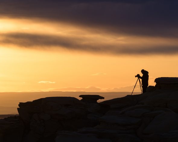 Photographer against a vibrant sunrise sky